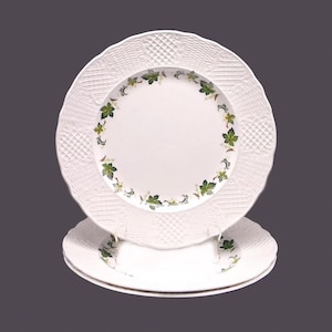May include: Set of three white ceramic dinner plates with a raised, embossed design and a green vine border.