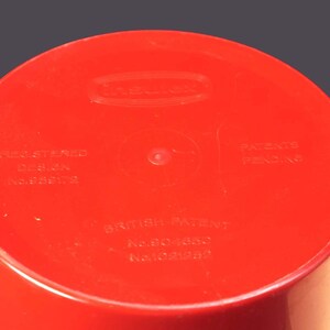 May include: Red plastic container with the text "Insinkerator" and "Registered Design No. 859172", "British Patent No. 804650", and "Patents Pending" printed on the bottom.