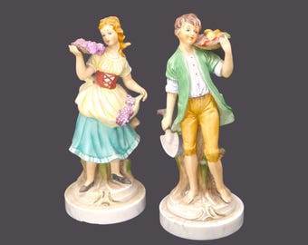 Pair of MCM porcelain bisque Capodimonte figurines on marble bases made in Italy. Girl with grapes, boy with fruit, spade.