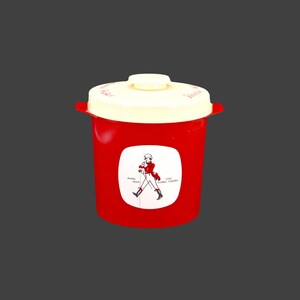 May include: Red plastic container with a white lid and a Johnnie Walker logo featuring a man in a red coat walking with a stick. The logo says "Born 1820 Still Going Strong".