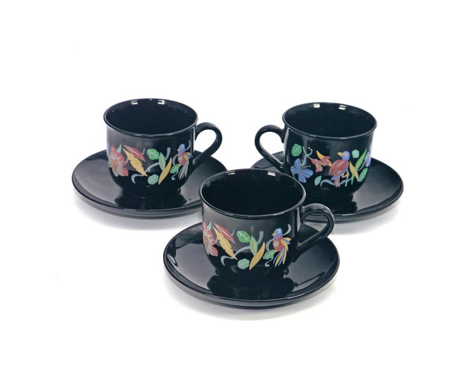 Three Arcoroc Arcopal cup and saucer sets. Multicolor florals and tropical birds on black glass. Made in France.