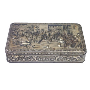 May include: Rectangular silver-toned metal box with a detailed relief scene of people in a tavern. The box features a decorative floral border and the word "Teniers" in elegant script. The lid depicts a lively gathering.