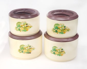 Four retro Sterilite plastic kitchen canisters. Fruit and vegetable imagery, brown lids. Made in USA.