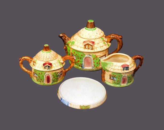 Ucagco Cottage Ware tea service made in Japan. Teapot with lid, trivet, sugar bowl, creamer. Thatched-roof cottage.