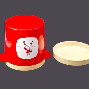 May include: A red plastic container with a white label that says "DOUBLE YOUR ENJOYMENT" and a picture of a person upside down. The container has a white lid.