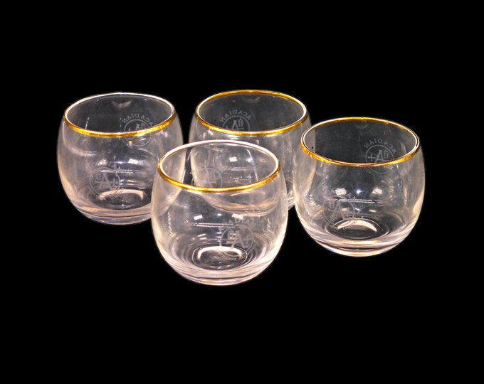 Four Acadian Distillers roly-poly lo-ball glasses with gold rims, etched-glass branding.