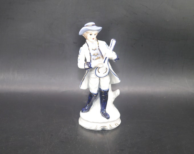 Dresden-style porcelain figurine young man in period Victorian dress playing mandolin.