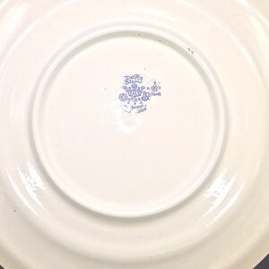May include: A white ceramic plate with a blue and white Delft Blue logo that reads "Delft Blau" and "Hand painted Holland".