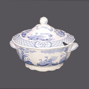 May include: A white porcelain tureen with a blue and white floral design. The tureen has a lid with a knob on top and two handles on the sides.