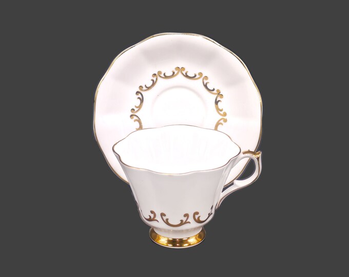 Queen Anne pattern 230 bone china cup and saucer set made in England. Embossed gold scrolls on white.