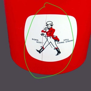 May include: A white circle with a red and black illustration of a man in a top hat and red coat walking with a cane. The text "Born 1820" and "Still Going Strong" are on either side of the man. The circle is on a red background.