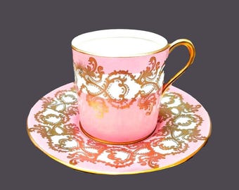 May include: A pink teacup and saucer set with a gold and white floral design.