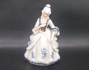 Dresden-style porcelain bisque figurine of woman in period Victorian dress.