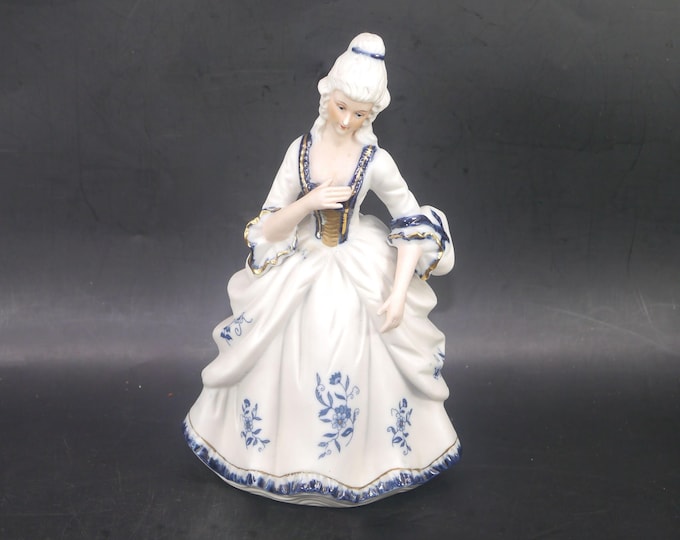 Dresden-style porcelain bisque figurine of woman in period Victorian dress.