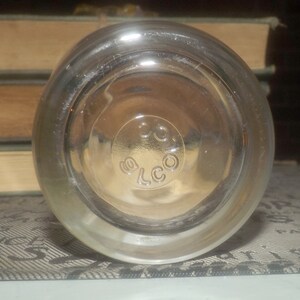 May include: Clear glass bottle with a textured surface and a circular label that reads "ELCO".