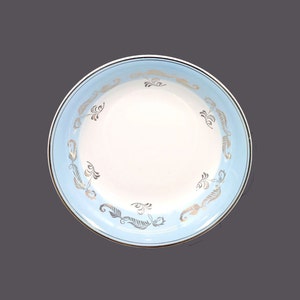 May include: A white ceramic bowl with a light blue rim and a gold floral design.