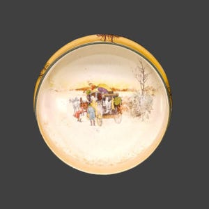 May include: A round, antique ceramic dish with a yellow rim and a detailed illustration of a horse-drawn carriage in a snowy landscape. The scene includes figures, trees, and a sunset.