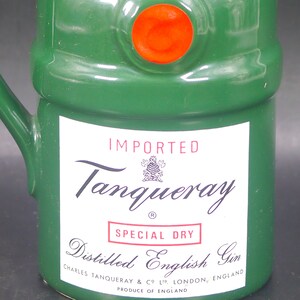 May include: A green ceramic bottle with a red seal and a white label. The label reads "IMPORTED Tanqueray SPECIAL DRY Distilled English Gin CHARLES TANQUERAY & CO LTD. LONDON, ENGLAND PRODUCE OF ENGLAND".