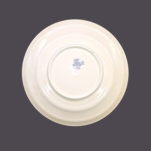 May include: The back of a white ceramic plate with a blue floral design and the text "Holly Hobbie - Made in Japan" in a blue circle.