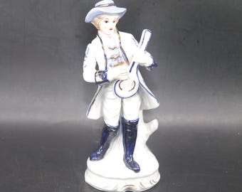Dresden-style porcelain figurine young man in period Victorian dress playing mandolin.