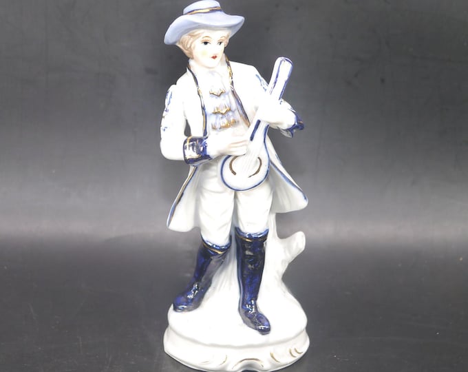 Dresden-style porcelain figurine young man in period Victorian dress playing mandolin.