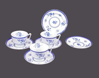 May include: Set of four blue and white floral teacups and saucers. The cups and saucers have a delicate floral pattern in blue on a white background.
