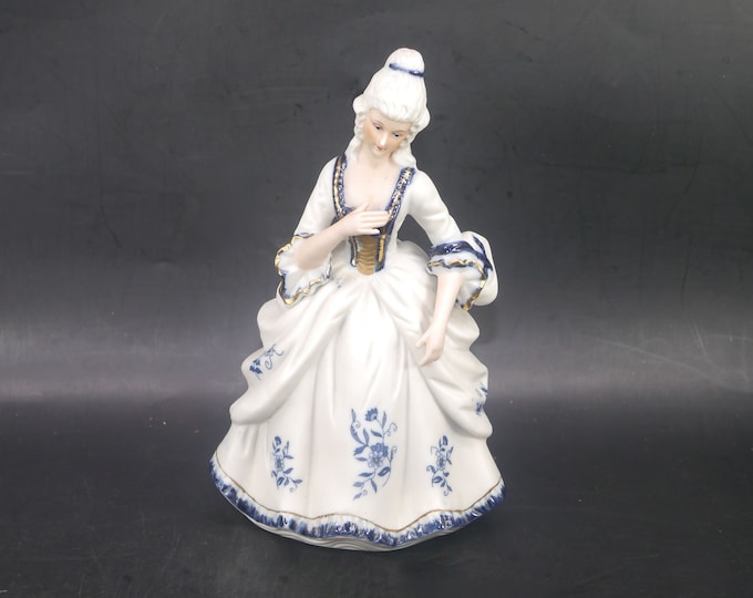 Dresden-style porcelain bisque figurine of woman in period Victorian dress.