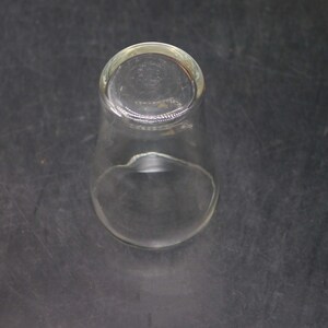 May include: A clear glass drinking glass with a rounded bottom and a wide mouth.