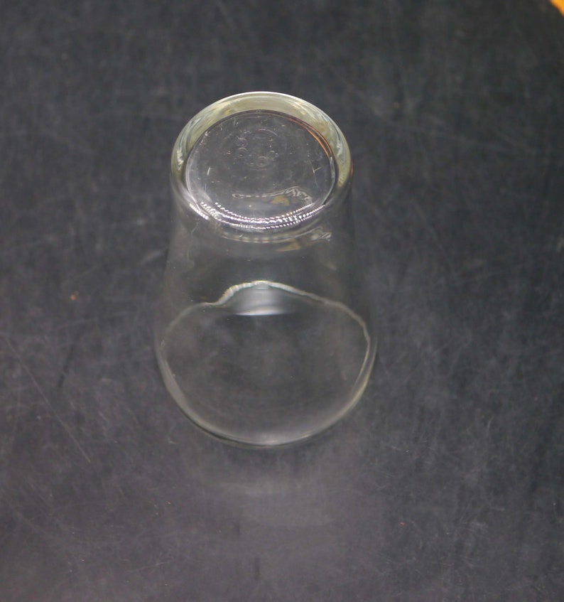 May include: A clear glass drinking glass with a rounded bottom and a wide mouth.