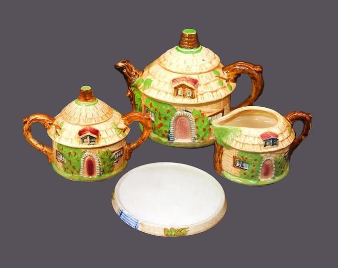 Ucagco Cottage Ware tea service made in Japan. Teapot with lid, trivet, sugar bowl, creamer. Thatched-roof cottage.