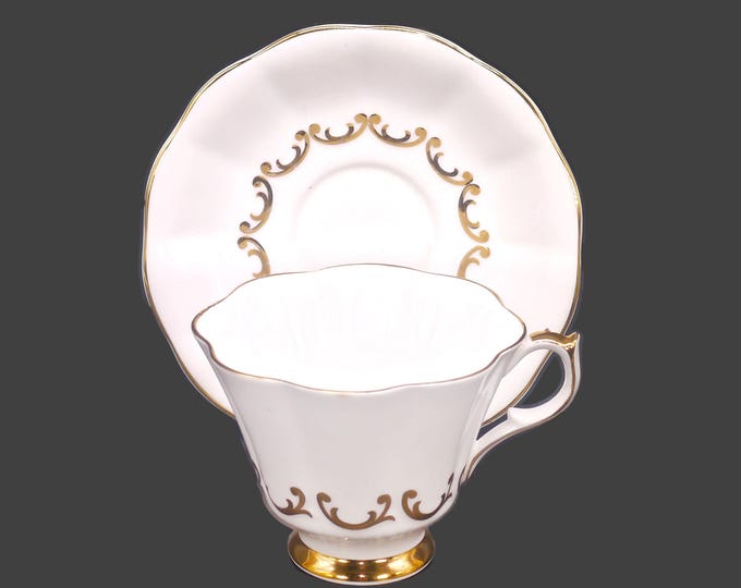 Queen Anne pattern 230 bone china cup and saucer set made in England. Embossed gold scrolls on white.