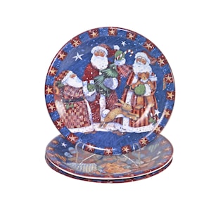 May include: Three blue and white ceramic plates with a Christmas theme. The plates feature a red and white Santa Claus, a red and white Santa Claus with a beard, and a red and white Santa Claus with a beard and a teddy bear. The plates are decorated with red and white stars and snowflakes.
