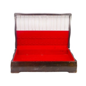 May include: An open, antique wooden jewellery box. It has a red velvet interior and a white, ribbed lining. The exterior is dark brown with a distressed finish. The box is empty and ready for use, showing signs of age.