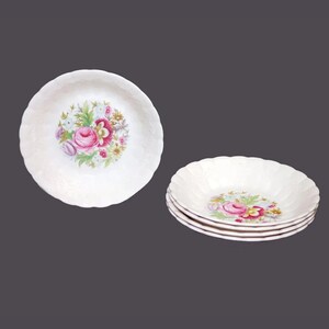May include: Set of six white ceramic bowls with a floral design. The bowls have a scalloped edge and a raised design on the bottom. The floral design features pink, red, and yellow flowers.