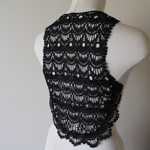 May include: Black crochet lace top with a scalloped design. The top is sleeveless and has a scoop neck.