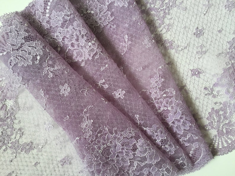K&ouml;nnte beinhalten: Lilafarbener Spitzenstoff mit einem zarten Blumenmuster. Die Spitze ist weich und durchscheinend und eignet sich perfekt f&uuml;r eine Vielzahl von Bastelprojekten.