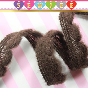 May include: Brown fuzzy trim with a scalloped edge. The trim is made of a soft, textured fabric.