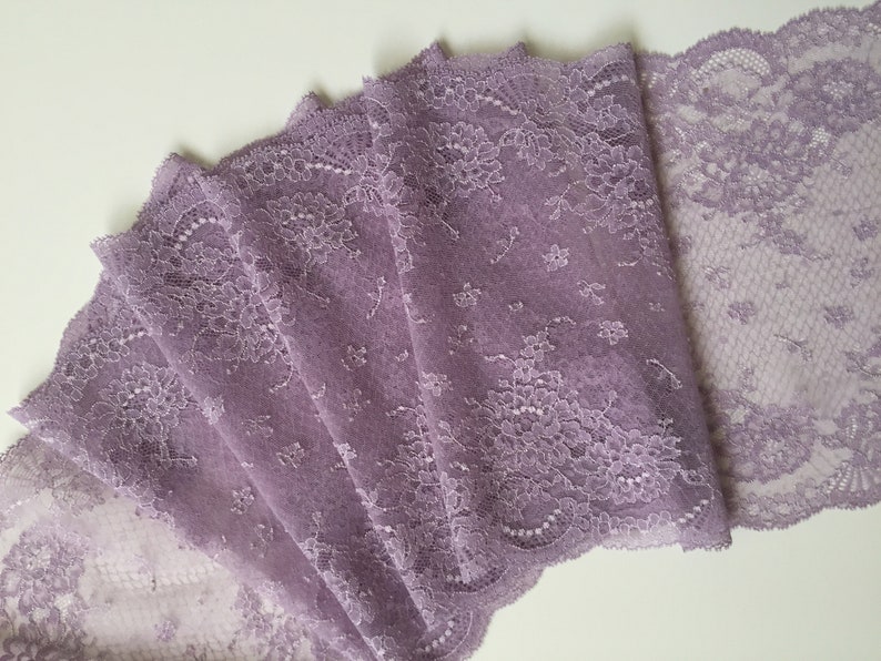 K&ouml;nnte beinhalten: Lilafarbener Spitzenbesatz mit floralem Muster. Die Spitze ist zart und hat einen gewellten Rand.