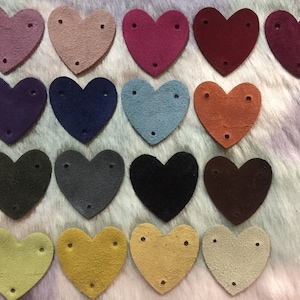 May include: Assortment of 18 heart-shaped suede patches in various colors, each with three holes. The colors include purple, pink, red, brown, blue, gray, black, green, yellow, and beige.