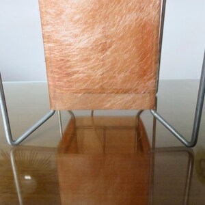 May include: A retro table lamp featuring a rectangular shade and a metal frame. The shade is a warm orange hue with a textured, fibrous appearance. The metal frame is silver and has a minimalist design.