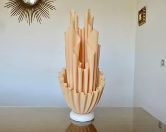 May include: A large, cream-colored, sculptural lamp with a ruffled, pleated design. The lamp is on a white marble base and has a modern, abstract look.