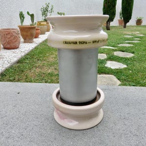 Può includere: Un condensatore cilindrico Ceraver TGPA 500 pF ± 10% dotato di un isolante in ceramica liscio color crema chiaro nella parte superiore e inferiore, collegato da un corpo centrale metallico color argento con testo nero sul bordo superiore.