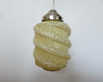 May include: A vintage pendant light with a spiral-shaped, cream-coloured glass shade. The shade has a textured, marbled appearance.