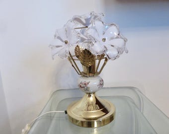 Könnte beinhalten: Eine goldene Tischlampe mit weißem Blumendesign. Die Lampe hat drei weiße Glasblüten als Lampenschirme.