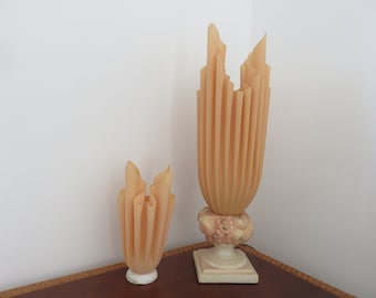 May include: Two beige ceramic lamps with pleated shades. The larger lamp has a decorative base with a floral design. The smaller lamp has a plain base.
