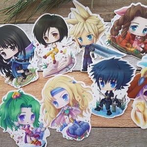 Puede incluir: Una colección de pegatinas coloridas de estilo chibi con personajes de videojuegos. Las pegatinas muestran personajes con ojos grandes y atuendos detallados, sobre un fondo blanco. Las pegatinas están dispuestas sobre una superficie de madera.