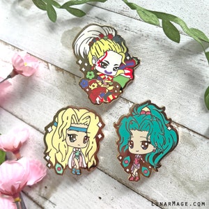 May include: Three enamel pins featuring anime-style characters. The pins are gold-toned and feature a variety of colors, including pink, blue, yellow, and green. The characters are depicted in a chibi style, with large heads and small bodies. The pins are perfect for adding a touch of whimsy to any bag, jacket, or hat.