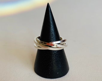 May include: A silver ring with multiple bands stacked on top of each other. The ring is displayed on a black cone-shaped ring holder.