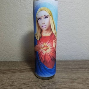 May include: A glass candle with a colorful image of a woman with a crown of thorns and a red heart with flames. The woman is wearing a blue robe.