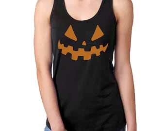 Może przedstawiać: Czarny podkoszulek z pomarańczową twarzą dyni. Bezrękawnik ma okrągły dekolt i jest wykonany z miękkiego materiału, idealny na Halloween lub imprezy tematyczne.
